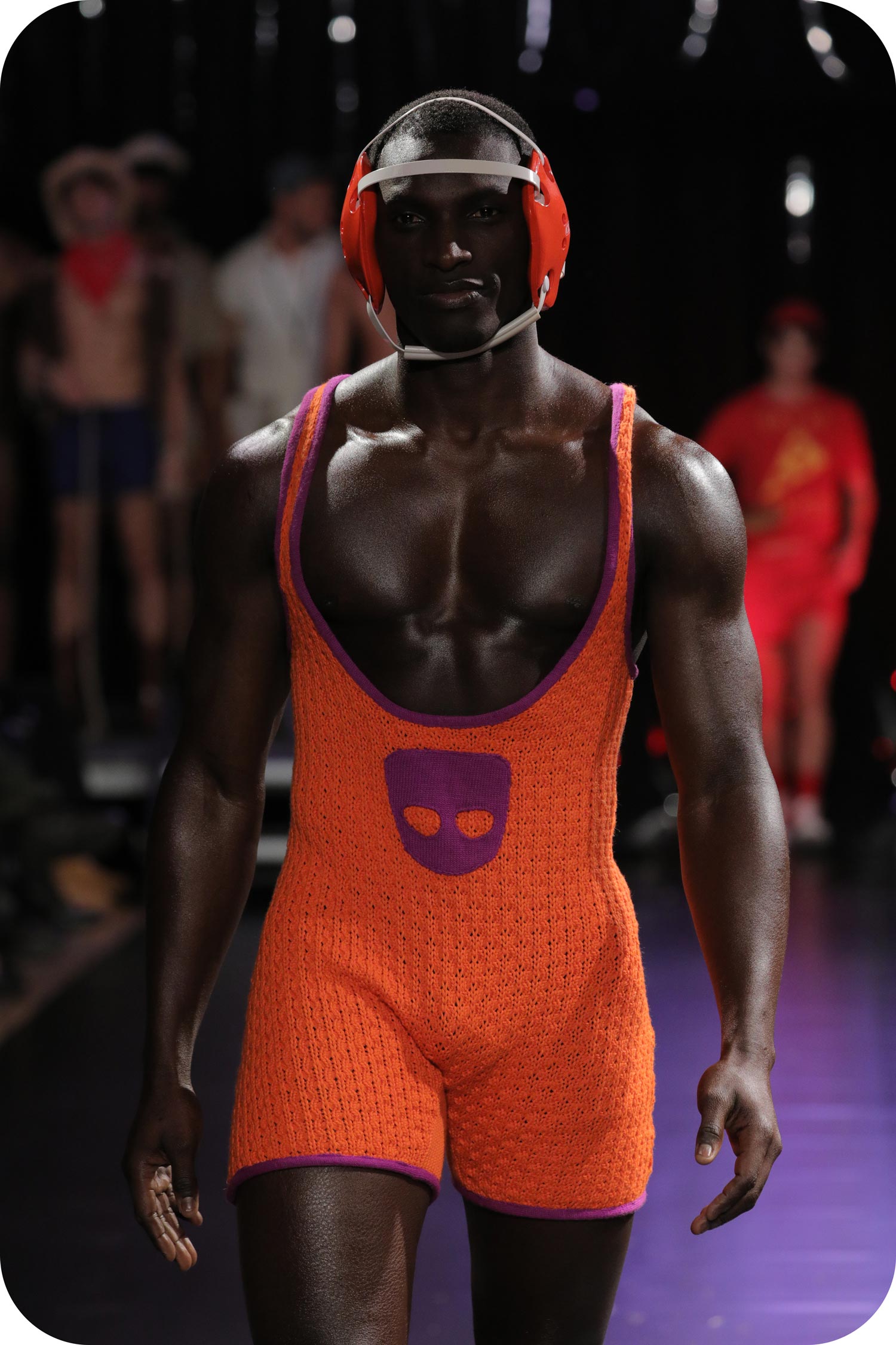 A man wearing an orange wrestler outfit with Grindr logo made of gay wool